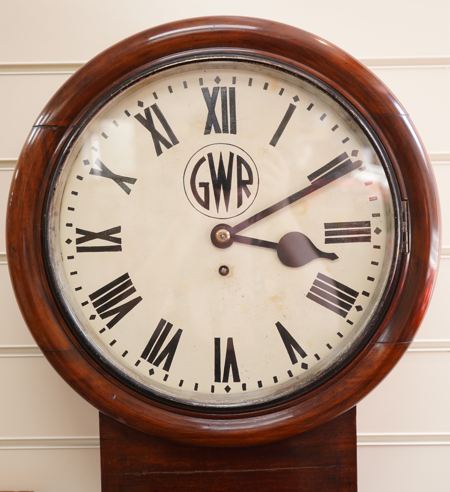 A GWR drop dial railway wall timepiece with fusee movement in a mahogany case, painted 12” dial with ‘shirt button’ GWR monogram and an ivorine plaque pinned to the lower left side of the case engraved with ‘GWR 3746’